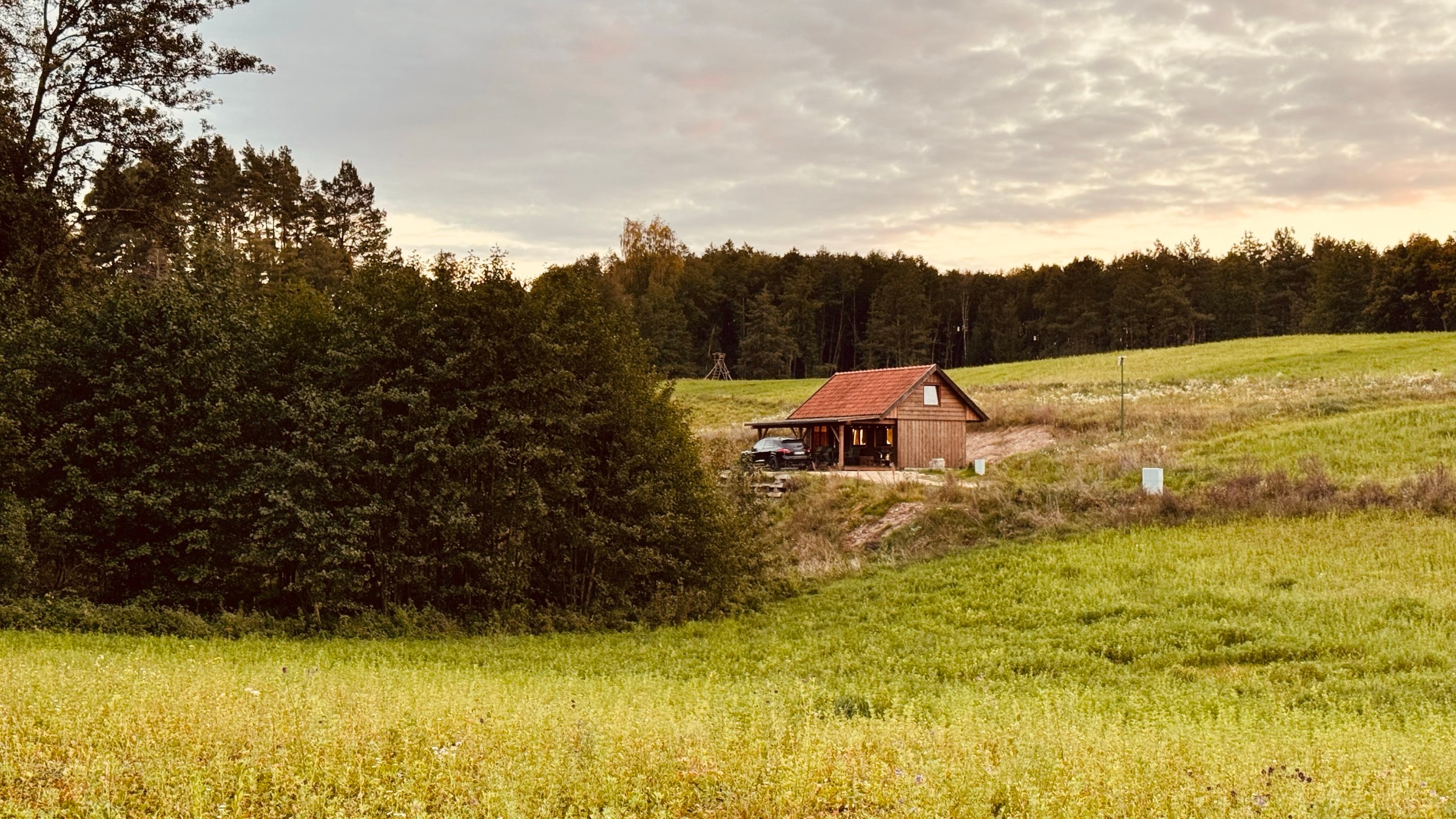Dobra Chata at dusk — wooden cabin with a hot tub at the forest edge in Masuria